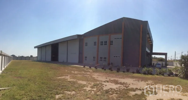 โรงงาน ขายในBang Sao Thong, Samut Prakan - มุมมองด้านข้างเต็มพื้นที่ผ่านแปลงหญ้าและถนนคอนกรีต.