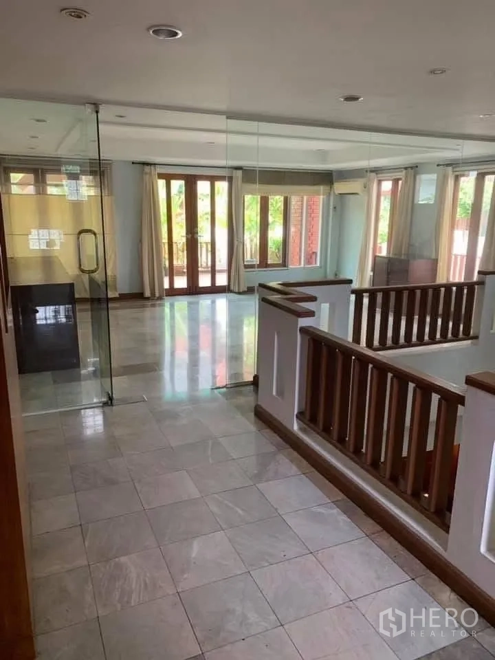 联排别墅 for rent in Watthana, Bangkok - 楼梯平台设玻璃隔间、石材地面与木扶手。