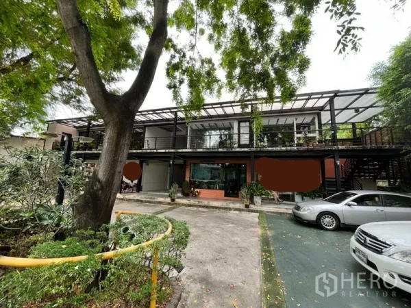 พื้นที่ขายปลีก ให้เช่าในWatthana, Bangkok - อาคารค้าปลีกสองชั้นทรงโมเดิร์น มีกระจกด้านหน้า ทางเดินมีหลังคา รายล้อมด้วยต้นไม้และที่จอดรถในโครงการย่านวัฒนา