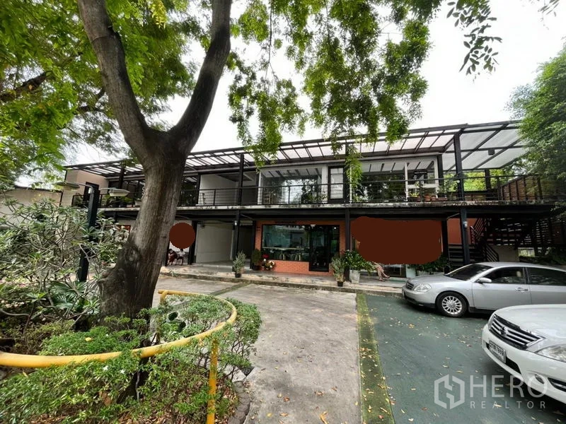 พื้นที่ขายปลีก ให้เช่าในWatthana, Bangkok - อาคารค้าปลีกสองชั้นทรงโมเดิร์น มีกระจกด้านหน้า ทางเดินมีหลังคา รายล้อมด้วยต้นไม้และที่จอดรถในโครงการย่านวัฒนา