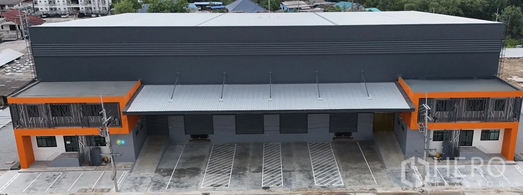 โรงงาน for rent in Bang Sao Thong, Samut Prakan - ด้านหน้าโกดังสไตล์โมเดิร์น มีกันสาดลานโหลด ประตูม้วน และที่จอดรถตีเส้น