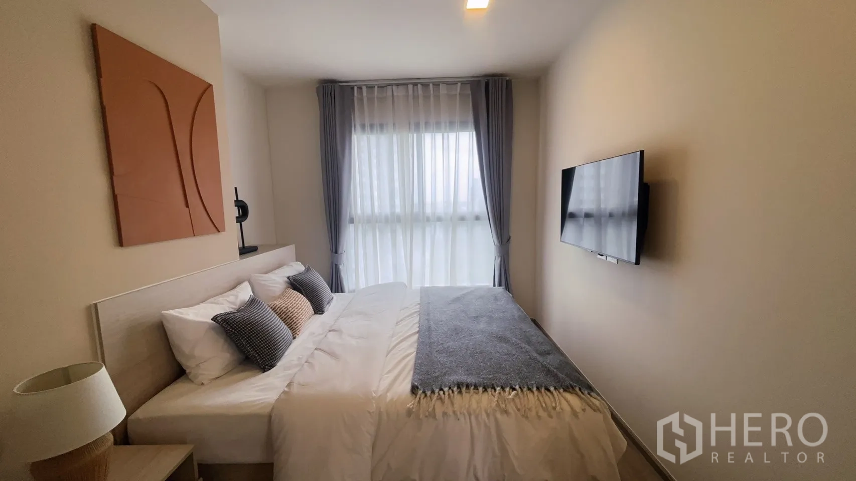Condominium for rent in Watthana, Bangkok - Bright bedroom with double bed, TV mounted on the wall, and wide window with sheer curtains.