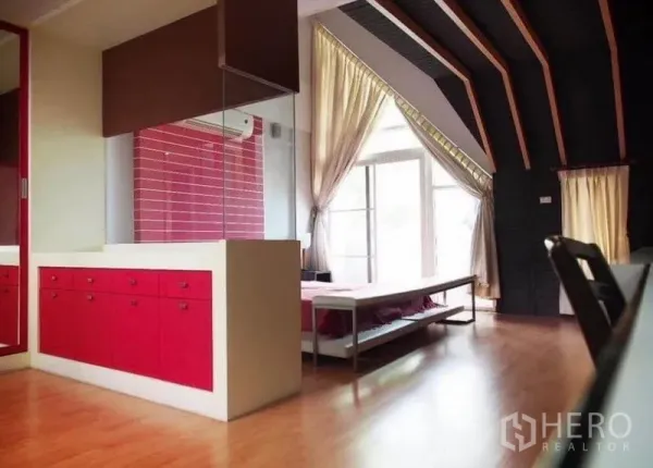 Townhouse for rent in Wang Thonglang, Bangkok - Loft-style master bedroom with vaulted ceiling, floor-to-ceiling windows, red cabinetry and warm wood floors.