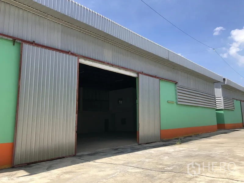 คลังสินค้า ให้เช่าในPathum Thani - ด้านหน้าโกดังพร้อมประตูเหล็กบานเลื่อนขนาดใหญ่และช่องระบายอากาศผนัง