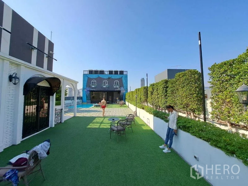 พื้นที่ขายปลีก ให้เช่าในWatthana, Bangkok - เทอเรซยาวขนานแนวรั้วพุ่มไม้ เชื่อมสนามหญ้ากับศาลาริมสระ