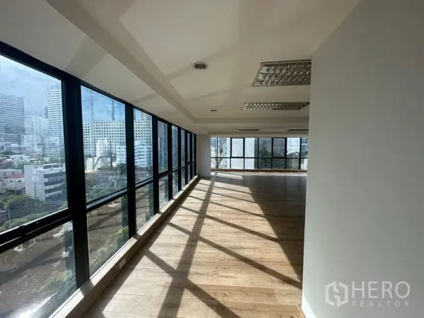 Office Space for rent in Sathon, Bangkok - Open-plan office corridor lined with floor-to-ceiling windows and wood floors overlooking the Bangkok skyline.