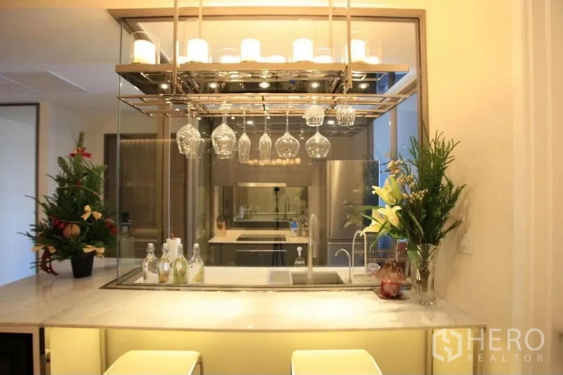 Condominium for rent or sale in Watthana, Bangkok - Modern kitchen bar with hanging wine glasses, marble countertop and sink.