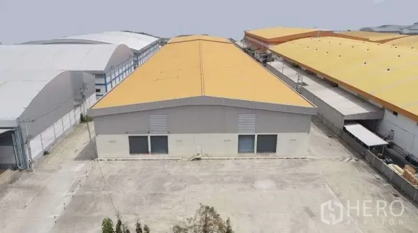 货栈 出租在Bang Bo, Samut Prakan - 工业园内黄色屋顶仓库的航拍图，宽阔混凝土庭院与装卸月台。