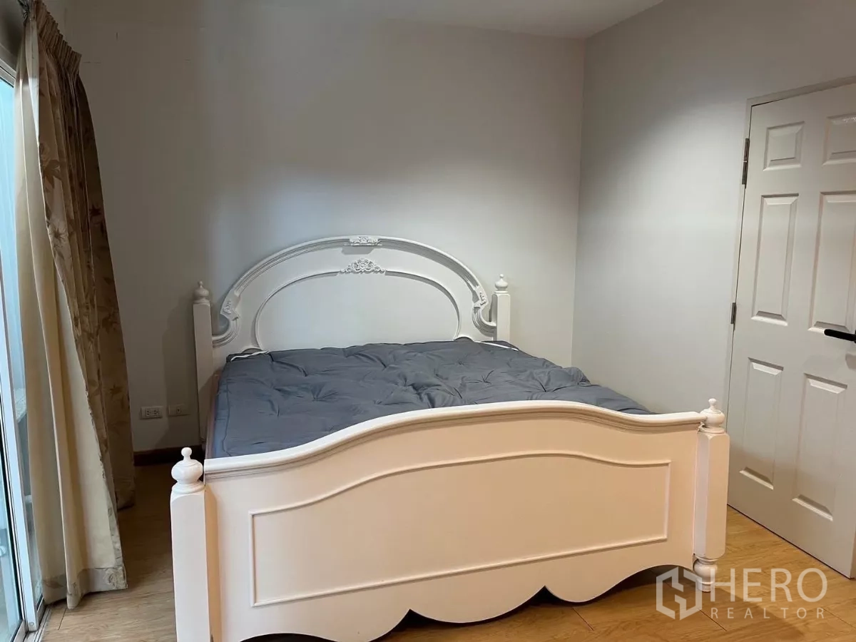 Townhouse for rent in Bang Kho Laem, Bangkok - Bedroom with white carved bed and sliding door to the balcony.