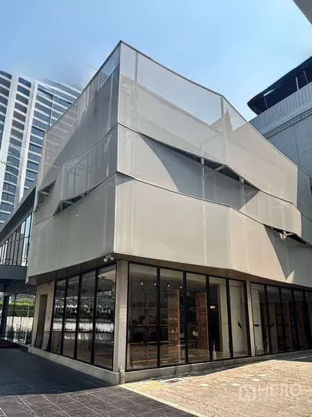 Retail Space for rent in Khlong Toei, Bangkok - Modern two-storey corner retail building with full-height glass facade on a city street.