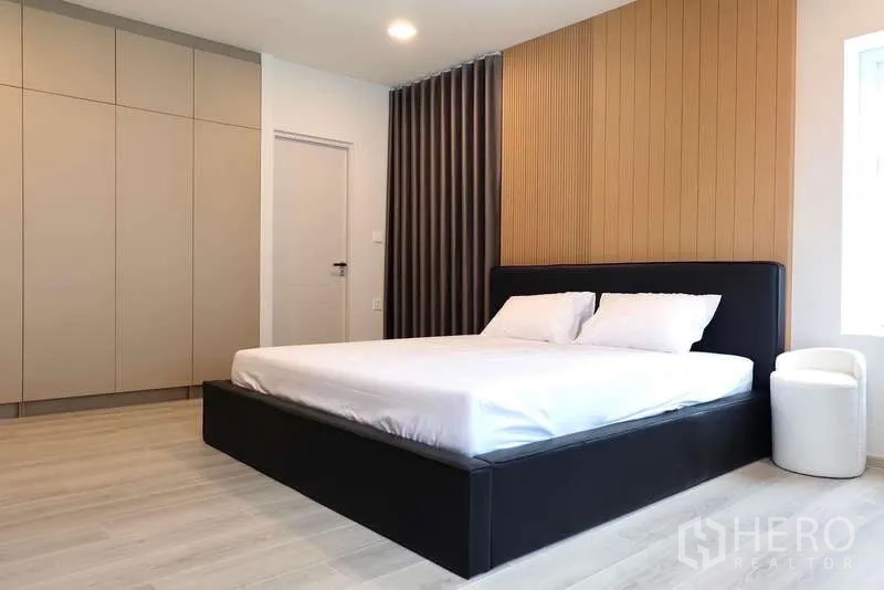 Detached House for rent in Bang Phli, Samut Prakan - Master bedroom with king bed, wood panel headboard and full-height wardrobes.