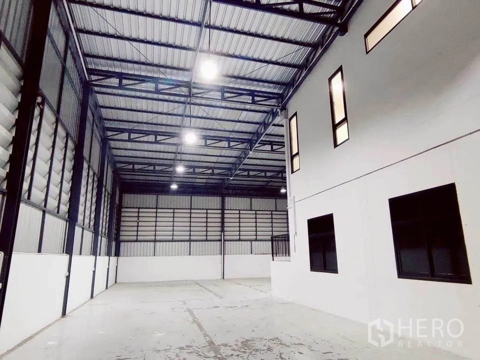 Warehouse for rent in Lam Luk Ka, Pathum Thani - High-bay storage area with steel beams and windows of the internal office.