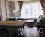 公寓 出租在Watthana, Bangkok - 通罗公寓客厅，沙发、电视柜、餐桌与通向阳台的大窗，采光充足