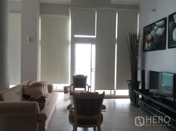 คอนโด ให้เช่าหรือขายในWatthana, Bangkok - ห้องนั่งเล่นเพดานสูง โปร่งสว่าง กระจกเต็มผนัง ม่านม้วน โซฟา และชั้นวางทีวี เปิดออกสู่ระเบียง