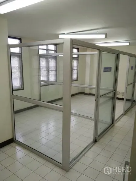 Townhouse for rent in Phra Khanong, Bangkok - Glass office cubicles inside a bright tiled room with strip lighting.