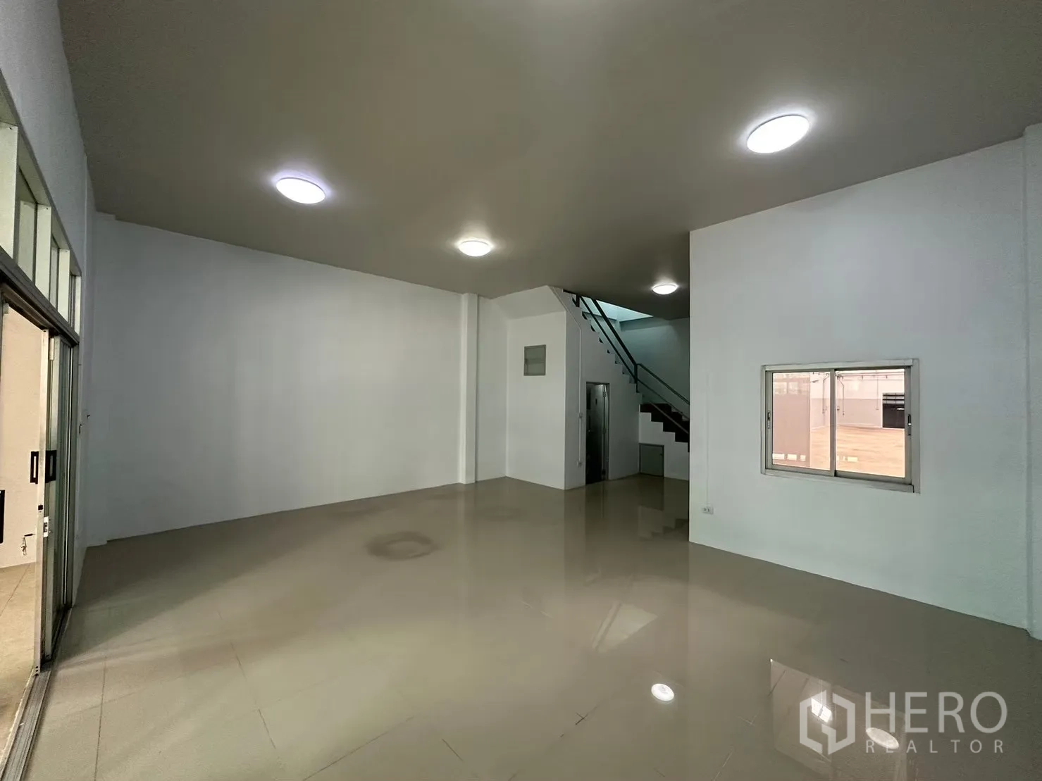 โรงงาน for rent in Bang Bua Thong, Nonthaburi - โถงชั้นล่างกว้างพื้นกระเบื้องเงาพร้อมบันไดและไฟเพดานสว่าง
