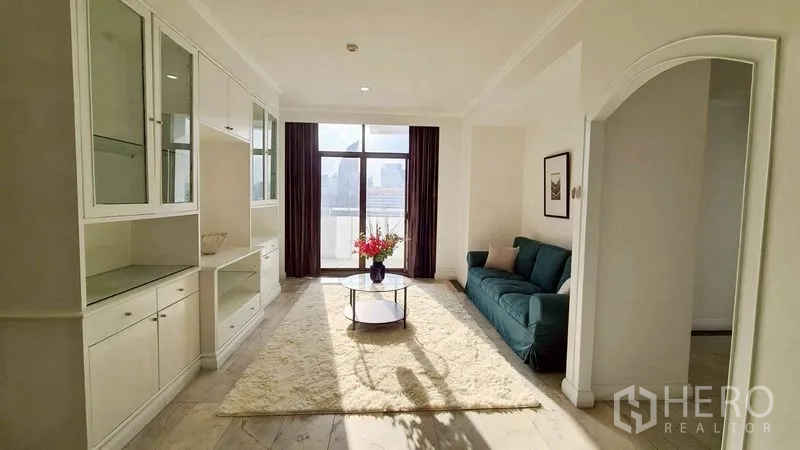 Condominium for rent in Watthana, Bangkok - Bright living room with built-in shelving, sofa, and large window.