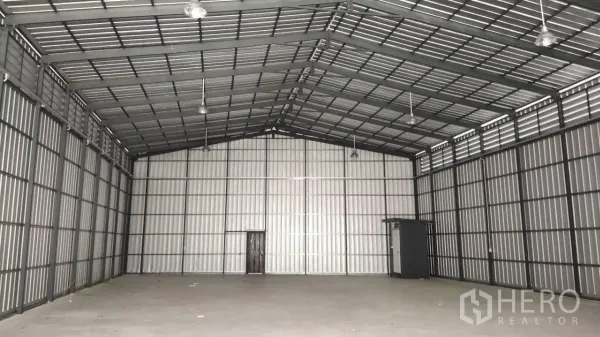 Warehouse for rent in Bang Lamung, Chon Buri - Empty storage hall showing gabled roof, ventilation louvers, and smooth concrete floor.