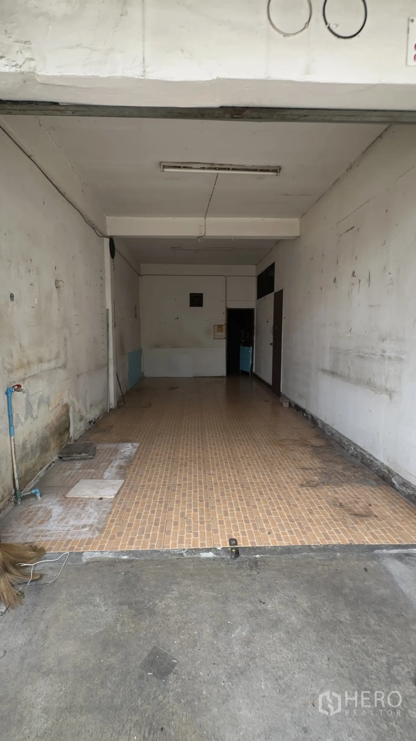 Shophouse for rent in Chatuchak, Bangkok - Front bay of the shophouse showing utility tap, long tiled floor and concrete apron for loading or parking.