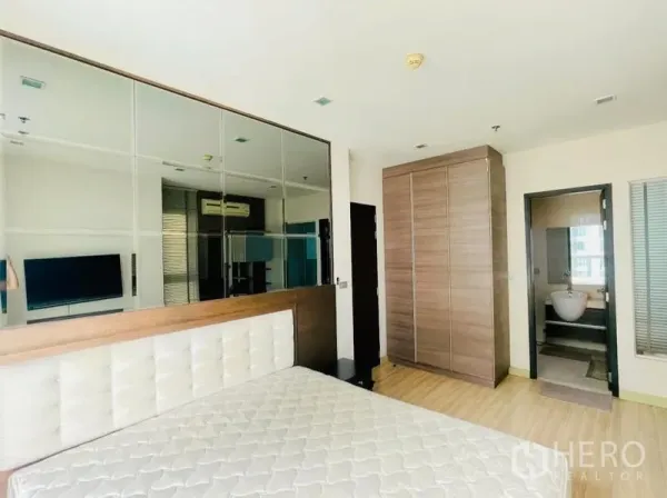 Condominium for rent - Spacious bedroom with mirrored feature wall, tall wardrobe, and entrance to the bathroom.