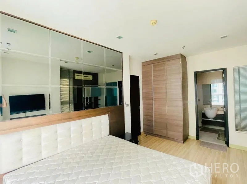 Condominium for rent - Spacious bedroom with mirrored feature wall, tall wardrobe, and entrance to the bathroom.