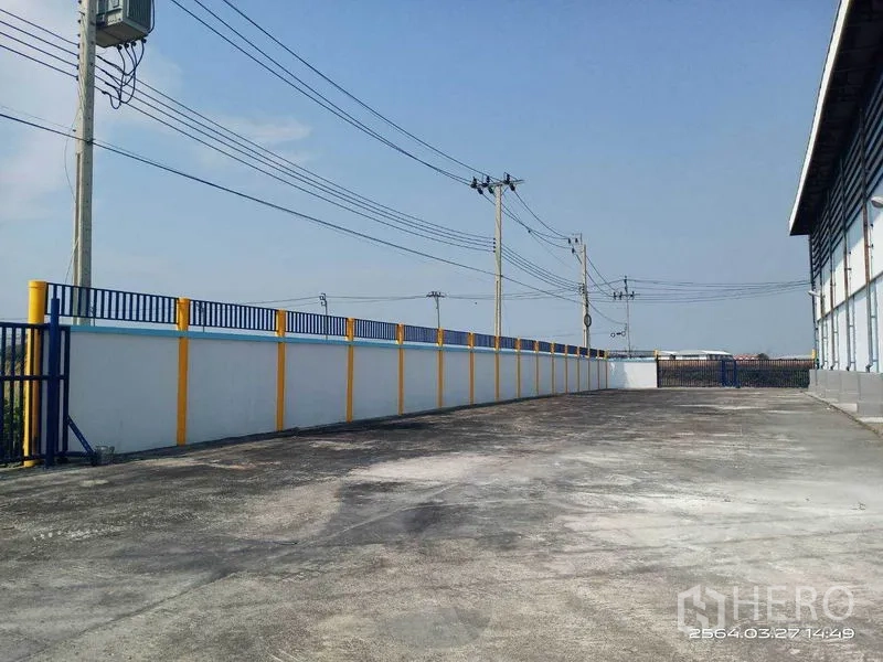 Warehouse for rent in Bang Bo, Samut Prakan - Asphalt loading area running the length of the warehouse and perimeter wall.