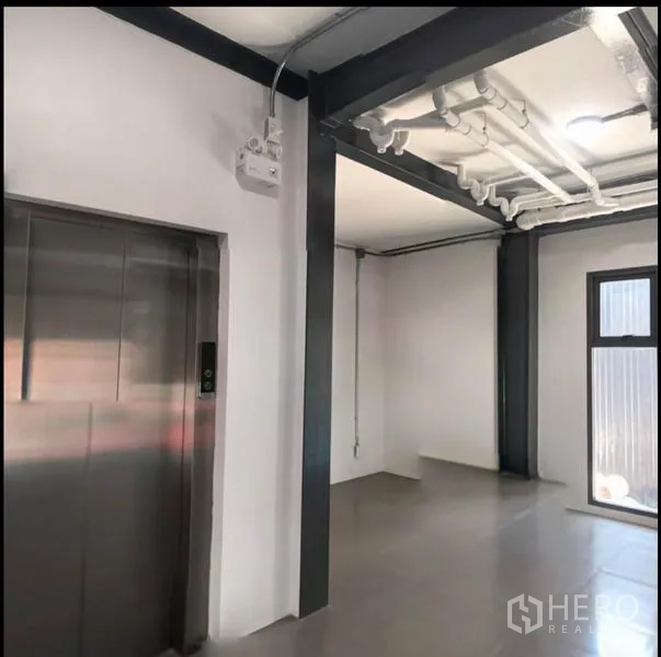 Office Space for rent in Wang Thonglang, Bangkok - Lobby with stainless steel elevator, exposed ceiling pipes and window lighting.