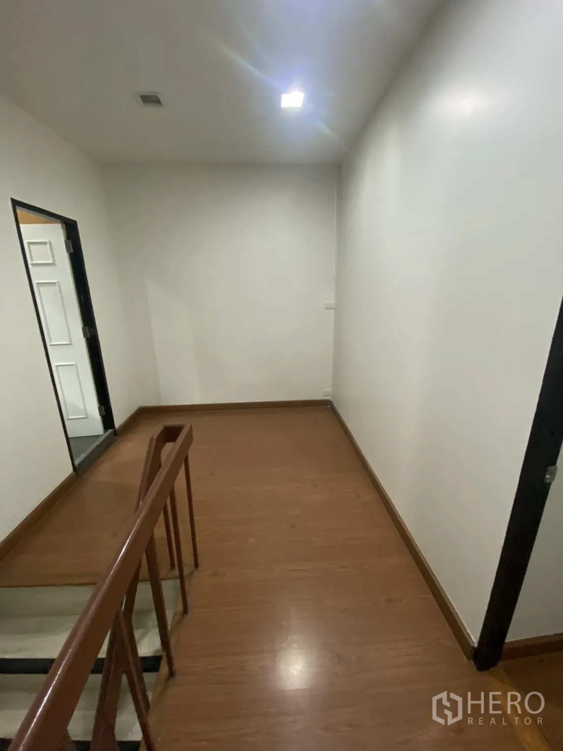 Shophouse for rent in Bang Rak, Bangkok - Upper landing with handrail and wood-look floor connecting rooms.