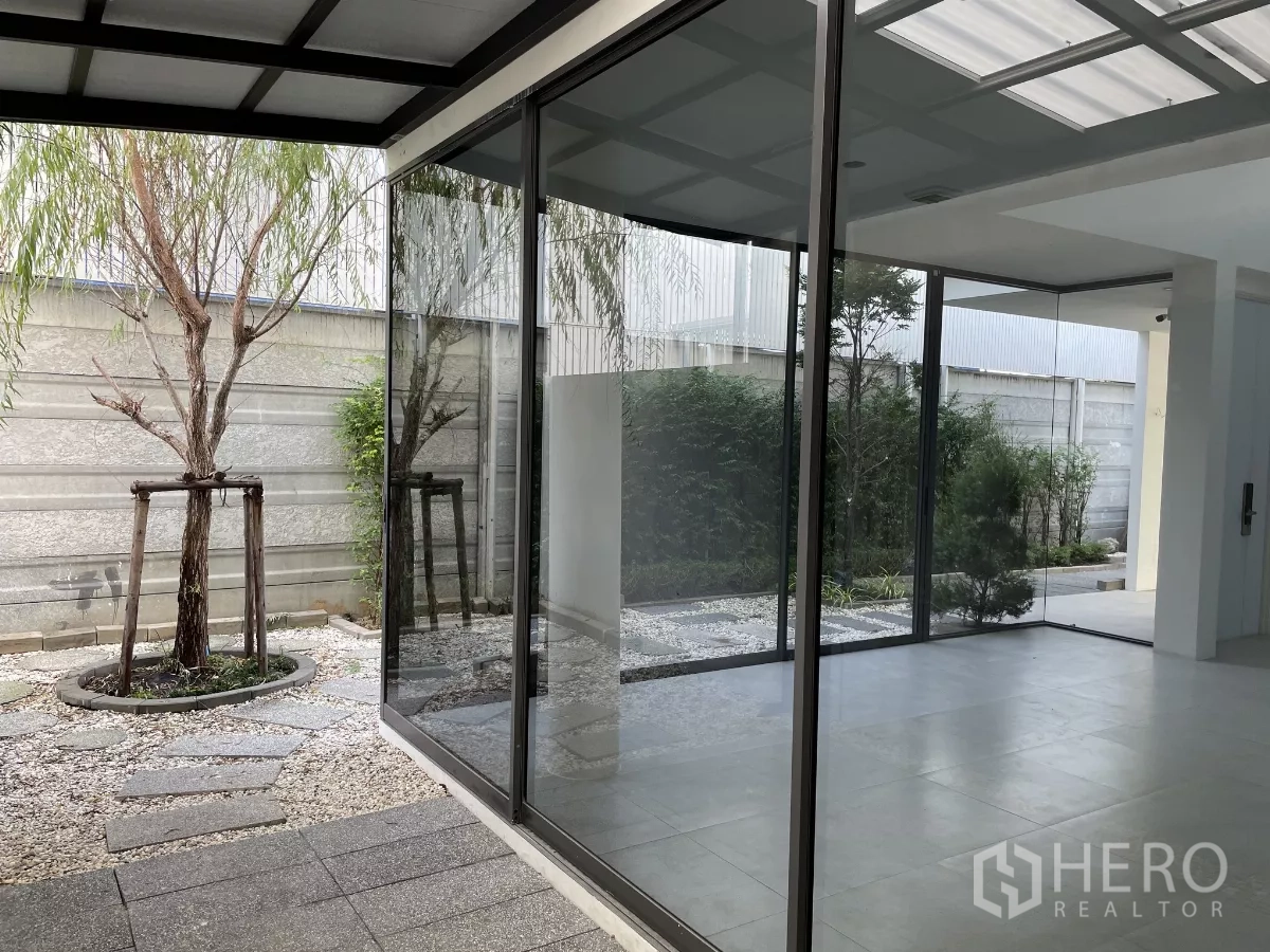 Home Office for rent in Don Mueang, Bangkok - Corner glass walls opening to a landscaped courtyard with stone path and trees.