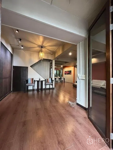 Townhouse for rent in Phaya Thai, Bangkok - Open-plan living area with wood floors, high ceiling and staircase leading upstairs.