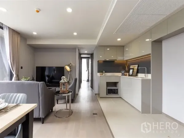 公寓 出租在Pathum Wan, Bangkok - 曼谷公寓的开放式客厅，灰色沙发、电视与简洁的整体厨房。
