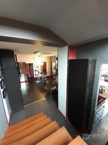 公寓 出租在Bang Na, Bangkok - 楼梯平台俯瞰现代厨房与休闲餐区，深色地砖