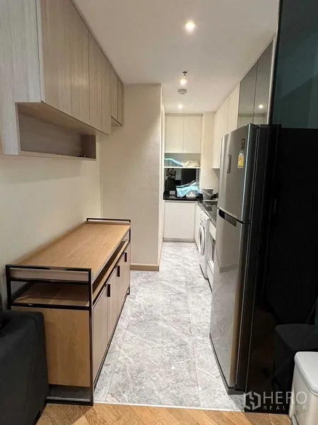 คอนโด ขายในWatthana, Bangkok - ครัวแบบแกลเลอรี ตู้ไม้สีอ่อน โต๊ะคอนโซล และพื้นกระเบื้องลายหิน