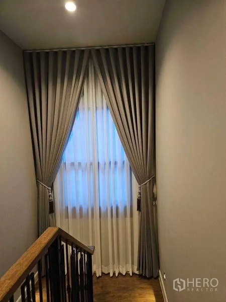 Detached House for rent in Mueang Pathum Thani, Pathum Thani - Stairwell landing with tall window and pleated drapes