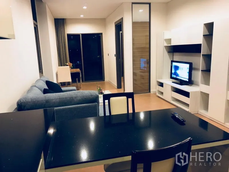 公寓 出租或出售在Bang Rak, Bangkok - 起居餐厅一体空间，电视柜、阳台推拉门与用餐台面。