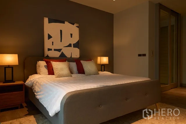 联排别墅 出租在Watthana, Bangkok - 温暖的主卧，特征墙、特大床与床头灯。