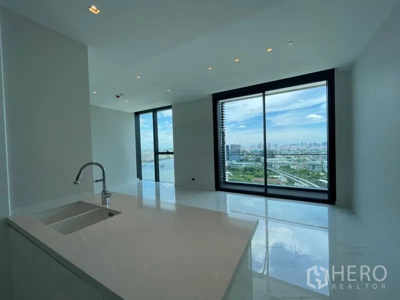 Condominium for rent or sale in Bangkok - Minimal open kitchen with island sink and expansive window framing river and city scenery.