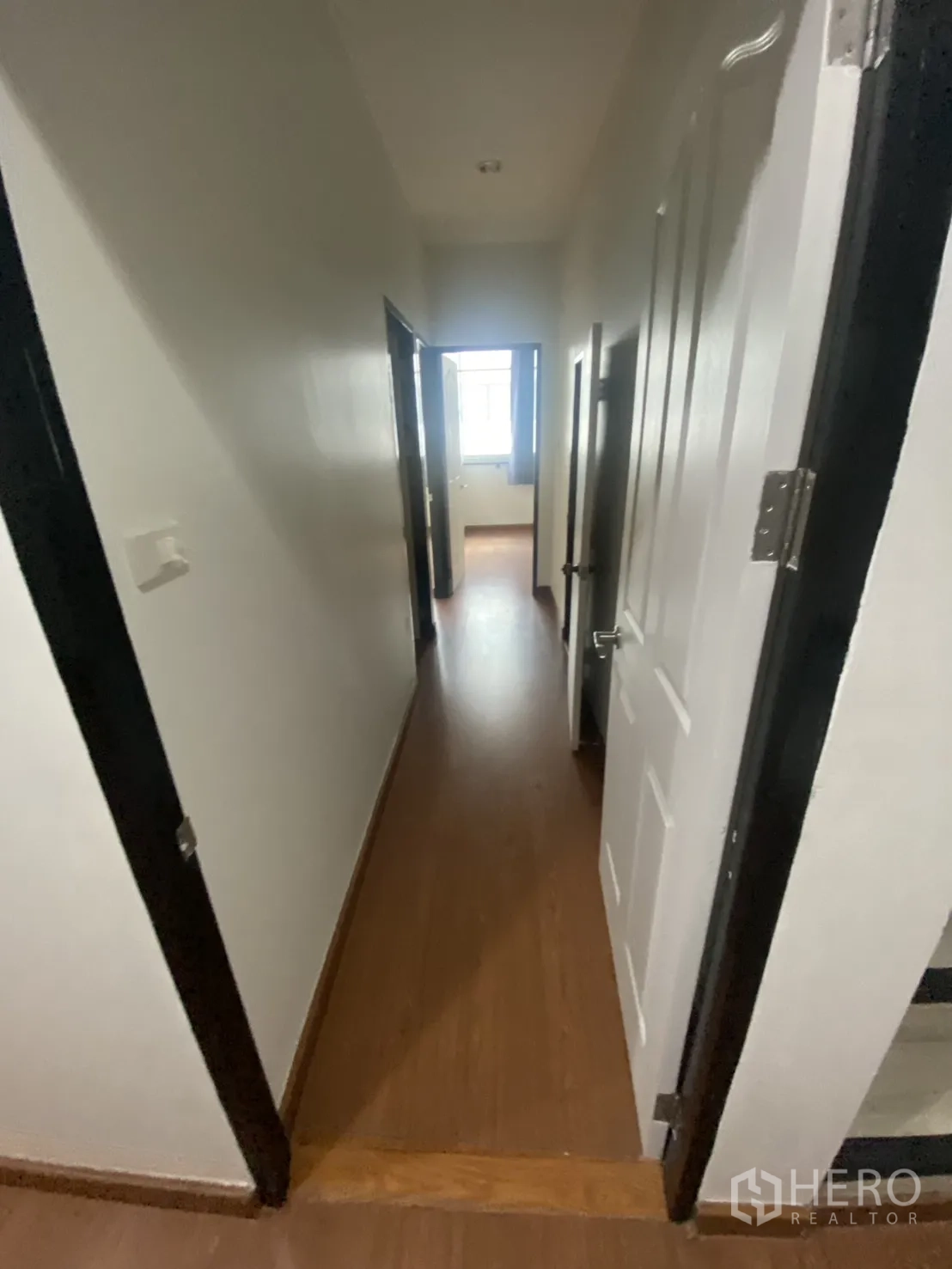 Shophouse for rent in Bang Rak, Bangkok - Corridor with multiple doors leading toward a bright window.