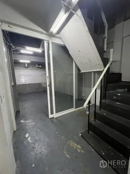 店屋 出租在Watthana, Bangkok - 后方服务区，黑色楼梯与玻璃推拉门。