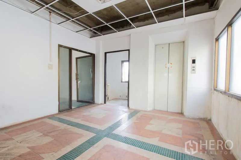 办公空间 出租或出售在Huai Khwang, Bangkok - 电梯前厅，带玻璃门、外露天花与图案地砖。