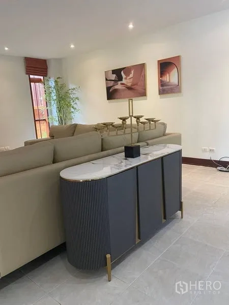 บ้าน ให้เช่าในSuan Luang, Bangkok - ห้องนั่งเล่นครอบครัวมีคอนโซลท็อปหินอ่อน โซฟาตัวแอล และไฟดาวน์ไลท์