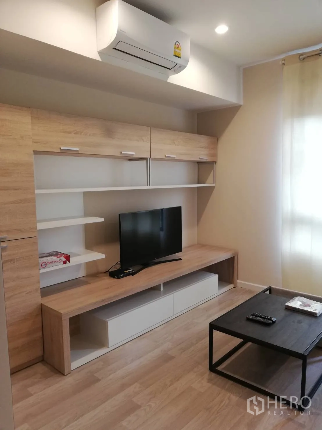 Townhouse for rent in Bang Kapi, Bangkok - Cozy living room with built-in TV cabinet, shelves, coffee table and wood flooring.
