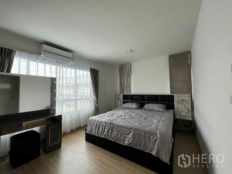 联排别墅 出租在Wang Thonglang, Bangkok - 明亮卧室，落地窗、空调、梳妆台与木地板。