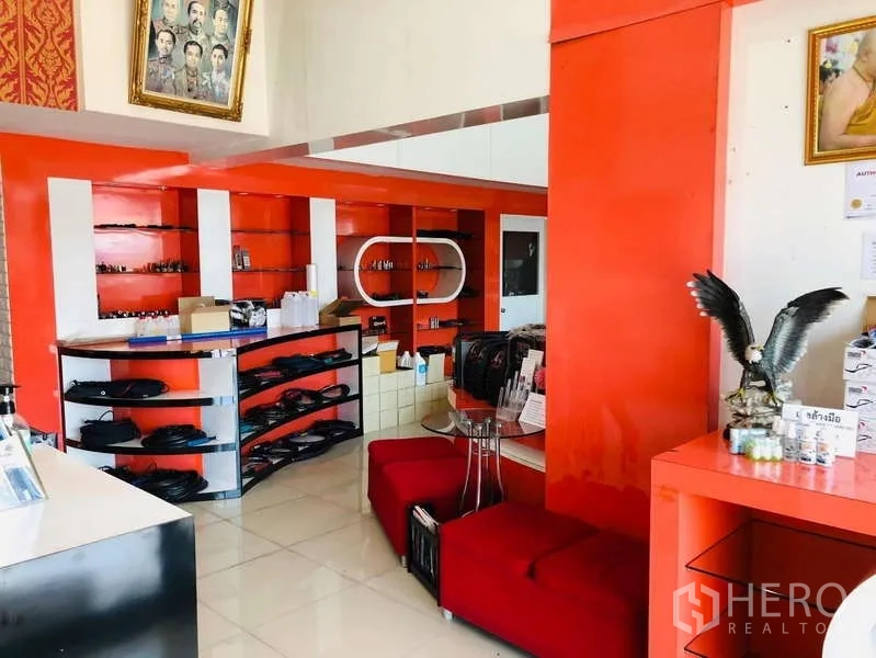 Shophouse for rent or sale in Bang Khun Thian, Bangkok - Retail space with curved shelving units, red seating and orange built-in display walls.