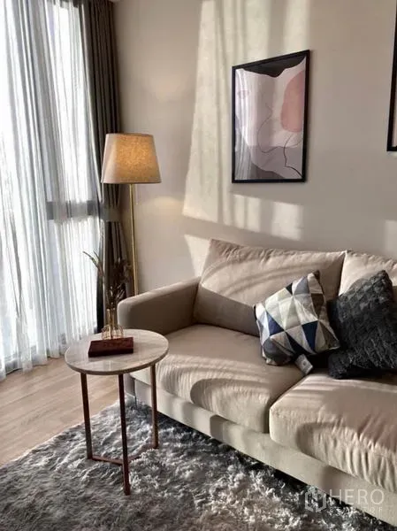 公寓 出租或出售在Phaya Thai, Bangkok - 温馨一隅：米色沙发、边几与落地灯，旁有轻薄窗帘。