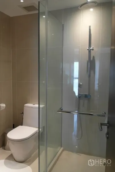 公寓 出租或出售在Sathon, Bangkok - 浴室配玻璃干湿分离，雨淋花洒与坐便器，浅色瓷砖。