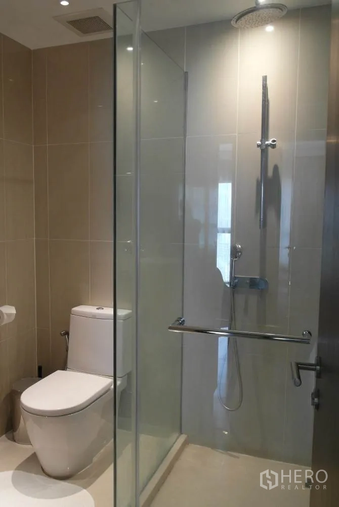 公寓 出租或出售在Sathon, Bangkok - 浴室配玻璃干湿分离，雨淋花洒与坐便器，浅色瓷砖。