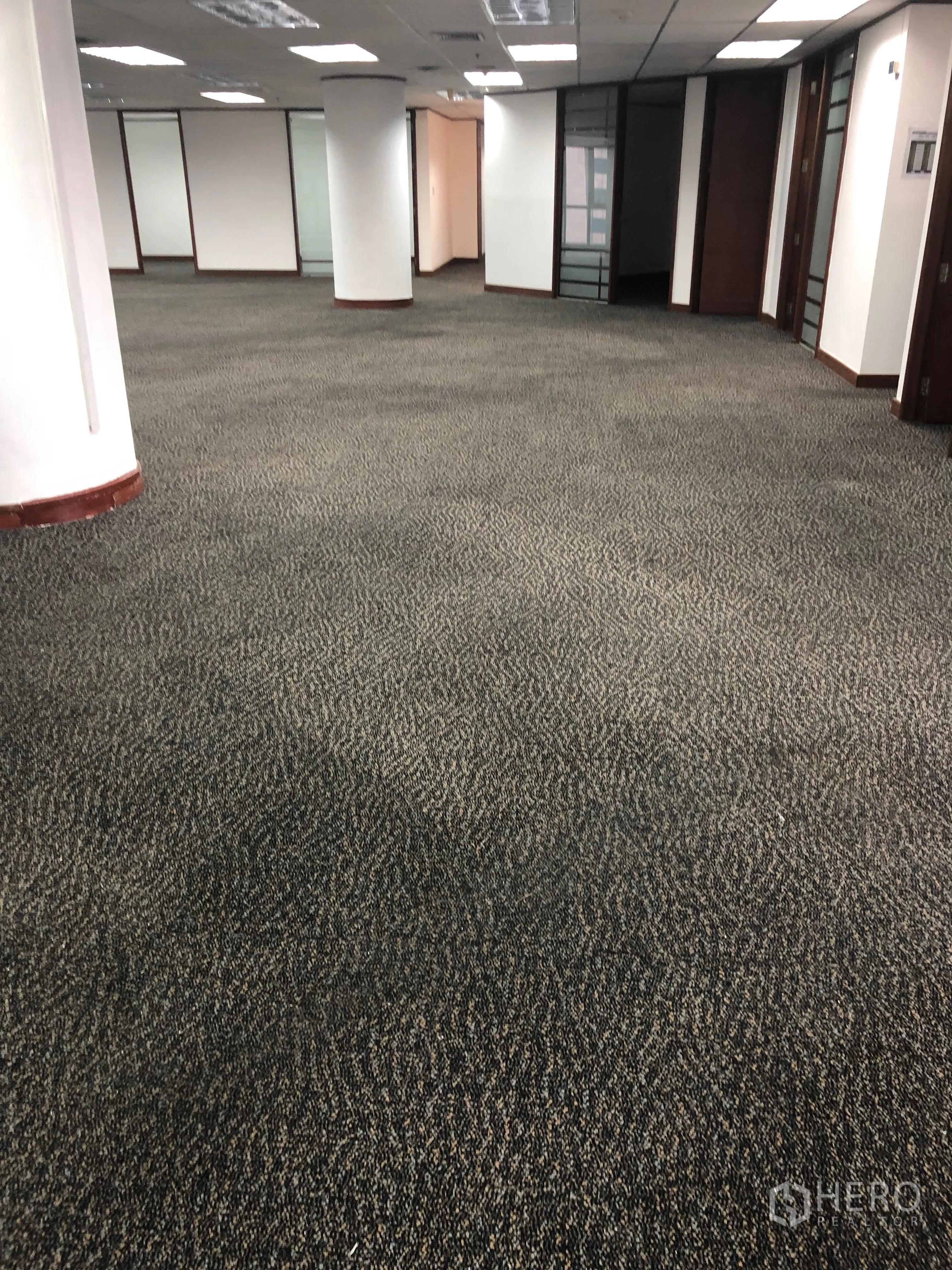Office Space for rent in Khlong Toei, Bangkok - Spacious office interior with carpet tiles, white columns and glass-partitioned rooms along the corridor.