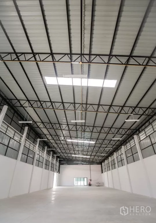 Factory for rent or sale in Bang Len, Nakhon Pathom - Close-up of the tall metal roof with skylights and hanging LED lights inside the factory.