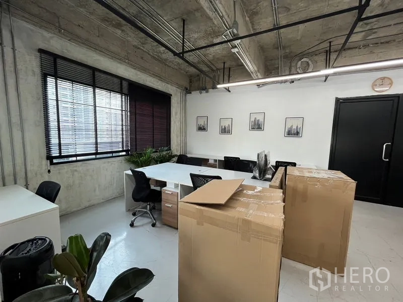 办公空间 出租在Khlong Toei, Bangkok - 靠窗的工位与会议区，白色桌面、黑色座椅、装饰画与深色门。